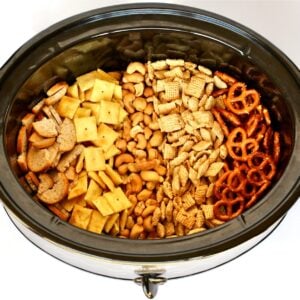 Lines of Chex mix ingredients in a slow cooker.