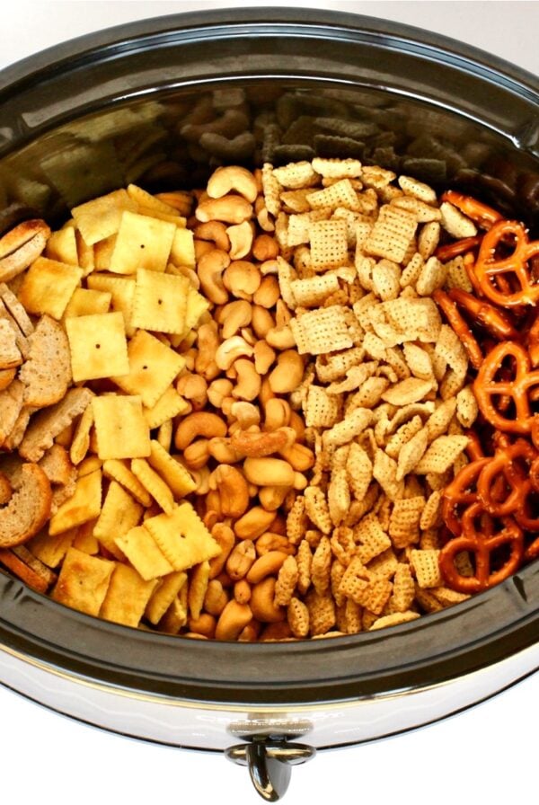 Lines of Chex mix ingredients in a slow cooker.