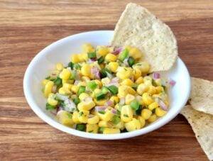 Chip in a bowl of chipotle corn salsa.