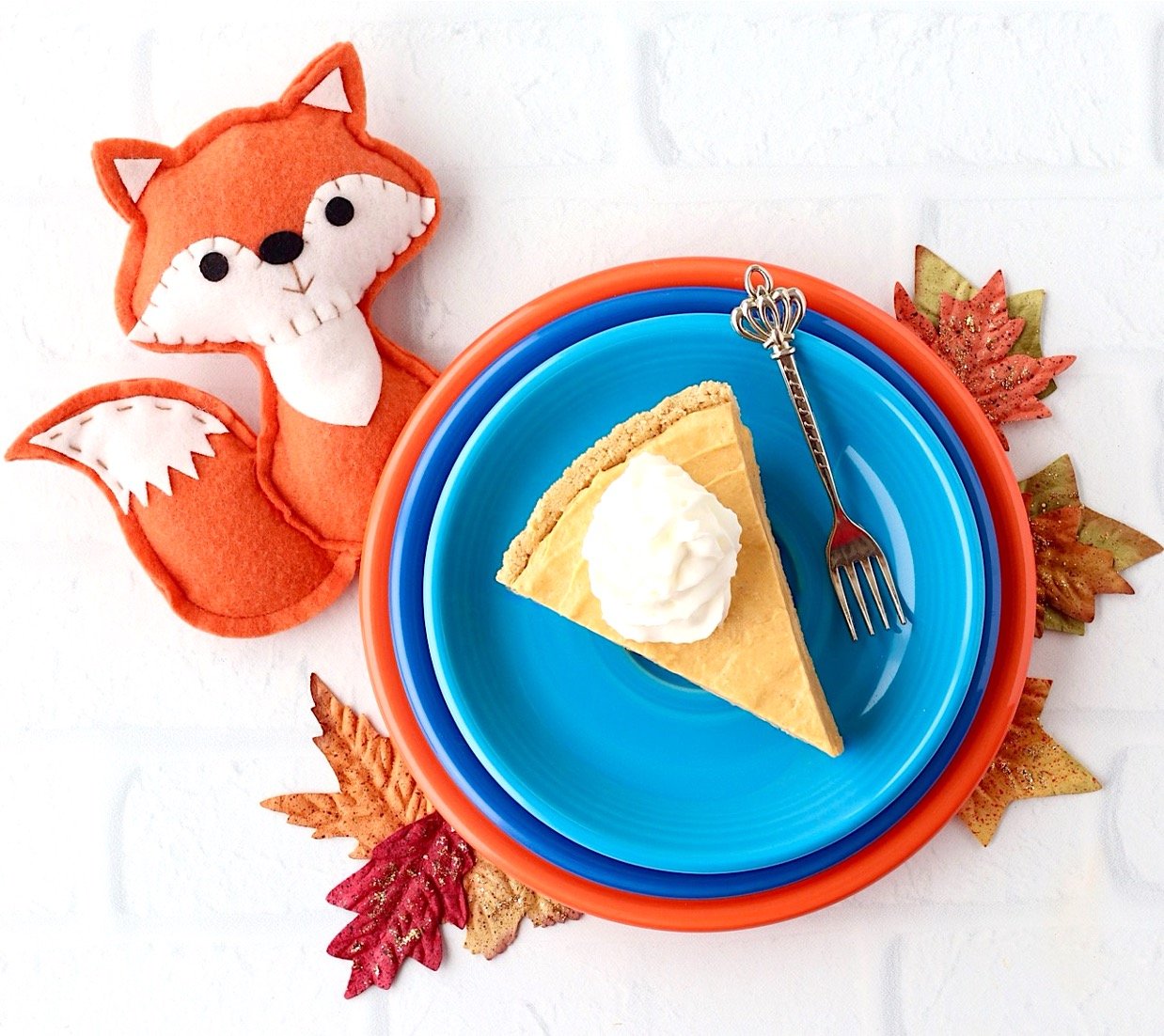 Slice of no bake pumpkin pie on plate with whipped cream on top.
