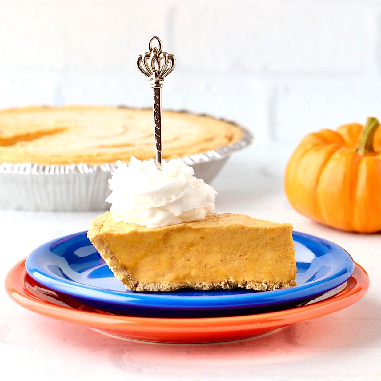 Slice of no bake pumpkin pie on plate with whipped cream on top and a fork.