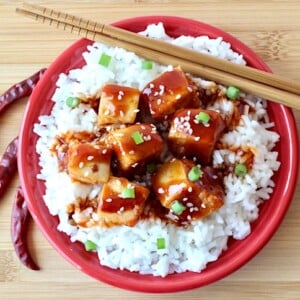 Chopsticks on a plate with General Tso Chicken and rice.
