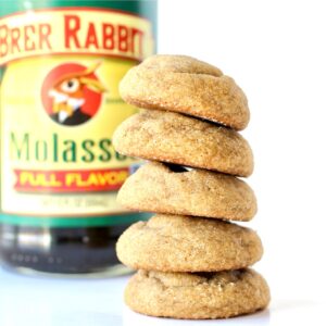 Stack of soft and chewy ginger snaps cookies with molasses bottle in background.