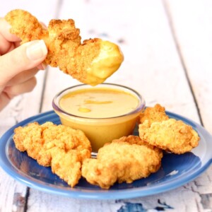 Person dipping chicken into honey mustard sauce.