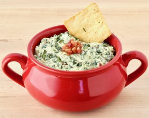 Red bowl of spinach dip.