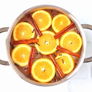 Cinnamon sticks and orange slices in a pot with water.
