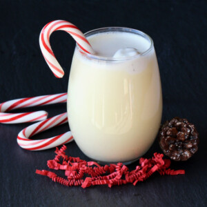 Candy cane in a glass of eggnog punch.