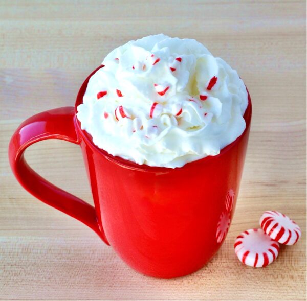 Peppermint mocha in mug topped with whipped cream and candy cane pieces.