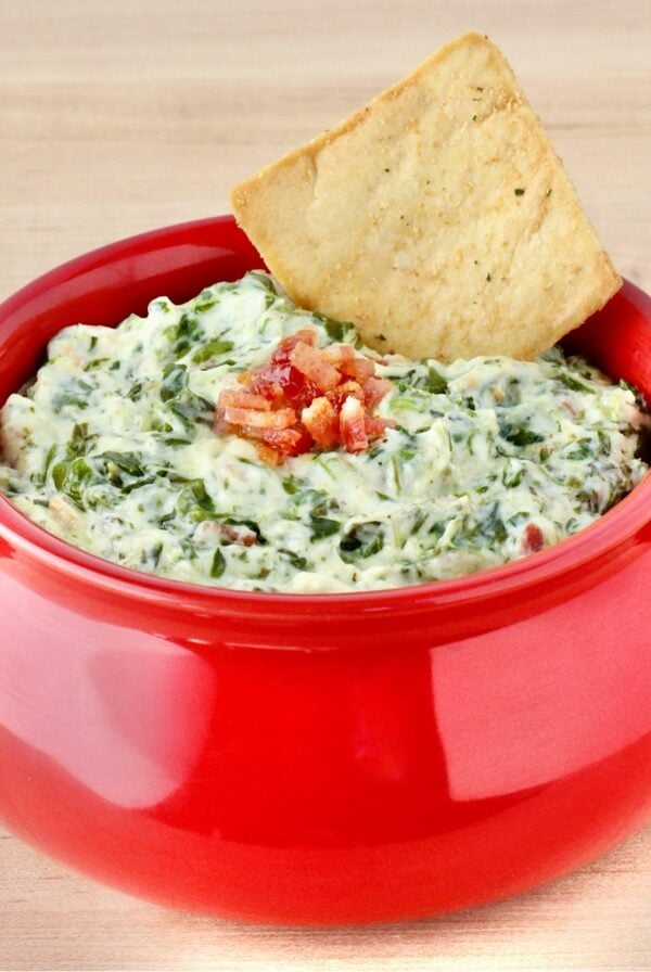 Spinach dip in red bowl with chip.