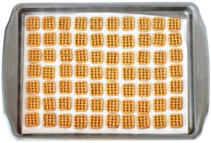 Lined baking sheet with square pretzels.