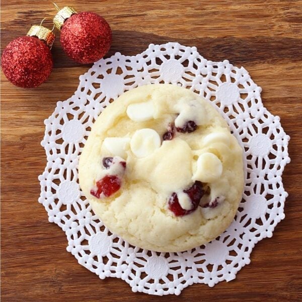 Cranberry cookie with white chocolate chips on a paper doily.
