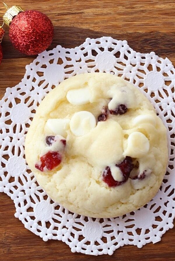 Cranberry cookie with white chocolate chips on a doily.