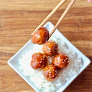 Chopsticks lifting a Hawaiian Sweet and Sour Meatball.