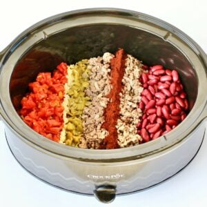 Beef chili ingredients unmixed in crock pot.