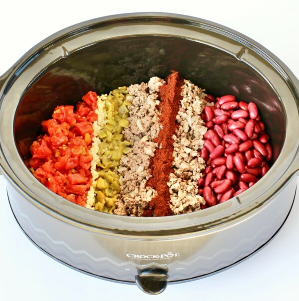 Beef chili ingredients in lines in crock pot.
