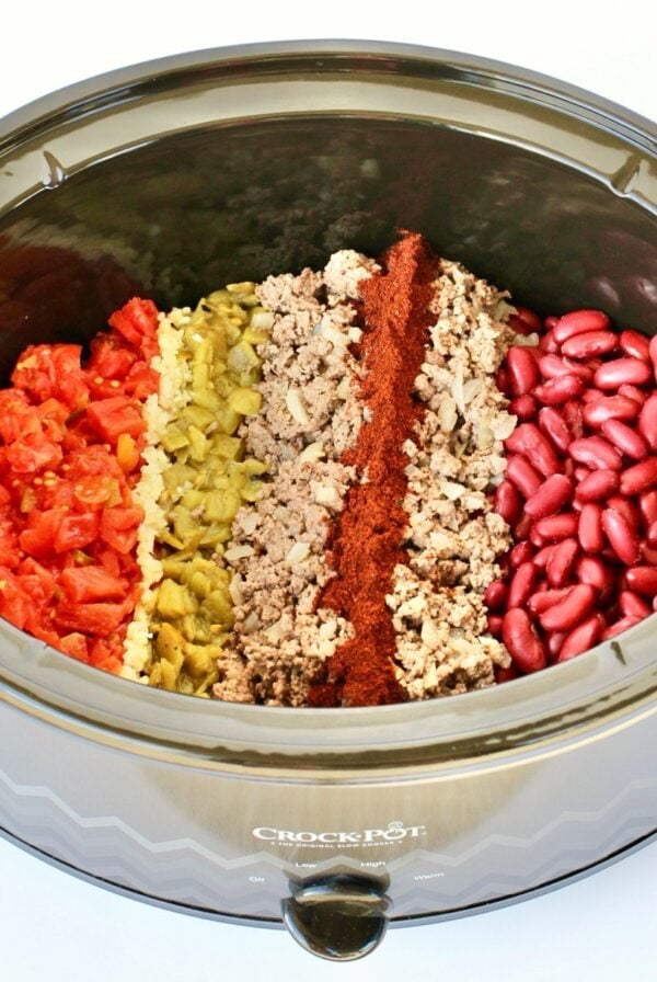 Beef chili ingredients unmixed in crock pot.