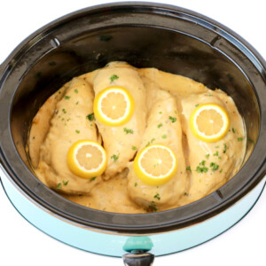 Chicken with lemon slices in a slow cooker.