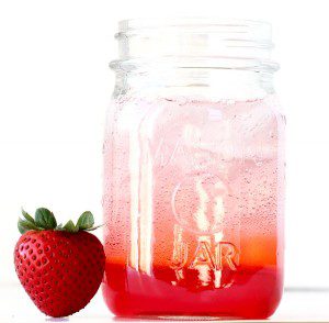 Layered club soda and strawberry syrup in a jar.