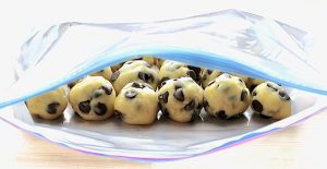 Balls of cookie dough in an open gallon bag.