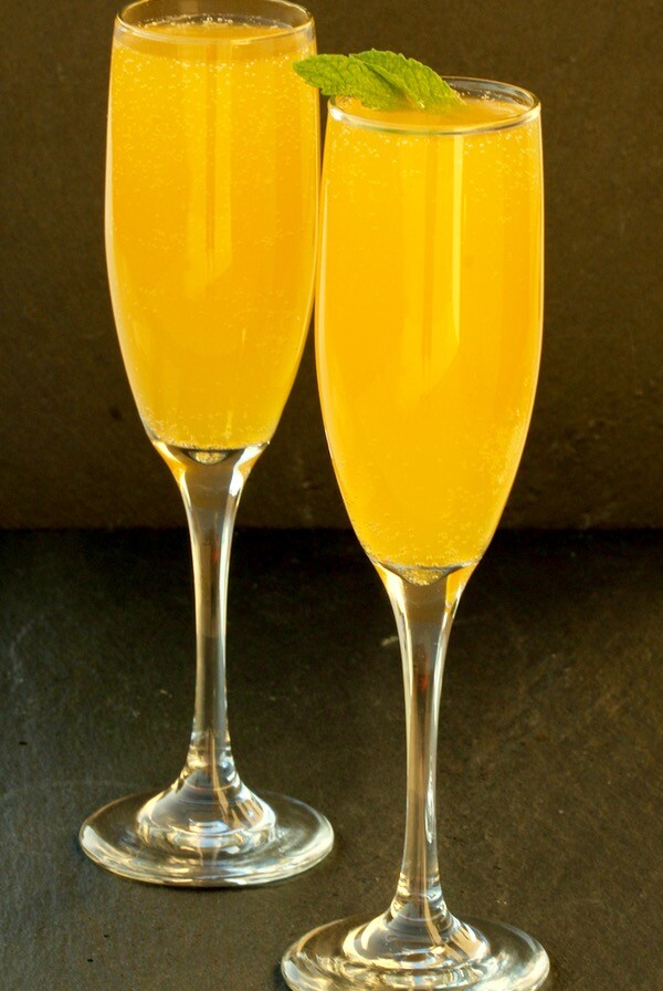 Stemmed glasses of peach mango Bellini mocktails.