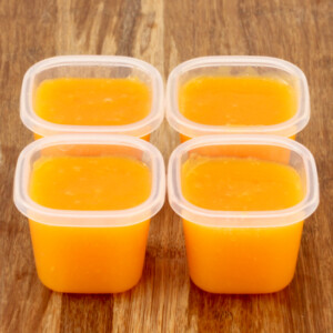 Four small containers of butternut squash baby food.