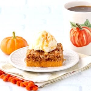 Slice of pumpkin dump cake on plate with vanilla ice cream scoop.
