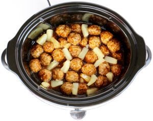 Meatballs and pineapple tidbits in a slow cooker.