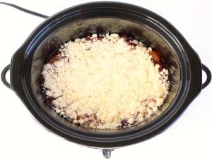 Crumble topping over fruit mixture in a slow cooker.