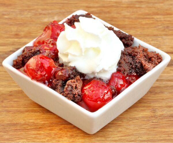 Chocolate Cherry Dump Cake in a square bowl topped with whipped cream.