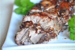 Cooked pork tenderloin on plate with glaze on top.