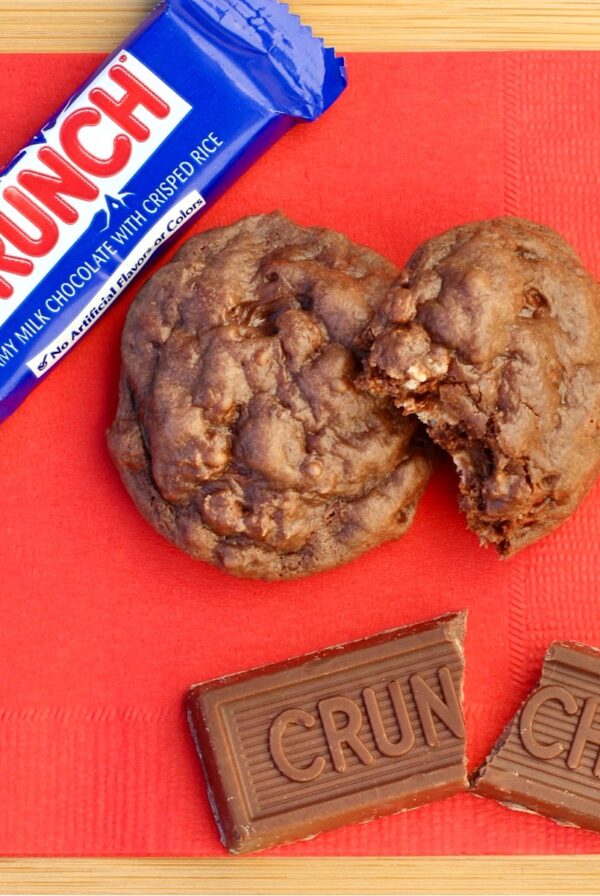 Chocolate cookies on red napkin with Nestle Crunch bars to the side.