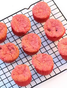 Strawberry angel food cake cupcakes sitting on a wire rack.