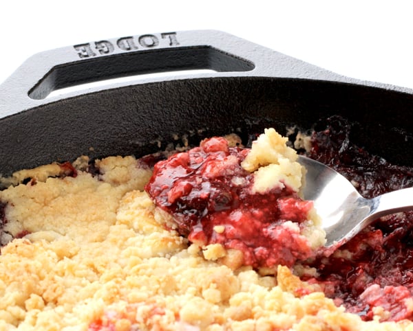 Spoonful of strawberry dump cake in cast iron skillet.