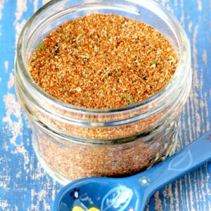Blue spoon next to a small jar of Blackened Chicken Rub.
