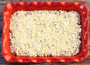 Crumble topping on apple filling in a baking dish.