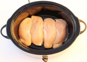 Chicken breasts in the bottom of a slow cooker.