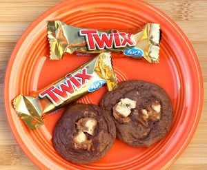 Two Twix Cookies on an orange plate with 2 mini Twix candy bars.