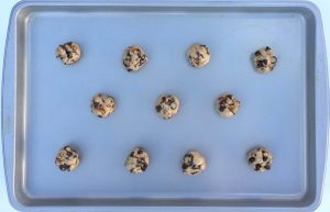 Balls of cookie dough on a lined baking sheet.