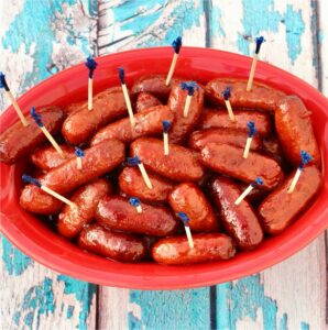 Lil smokies in grape jelly sauce in bowl, with toothpicks inserted.