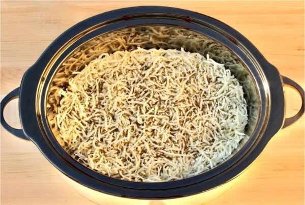 Sauce topped with cheese in a slow cooker.