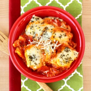 Red bowl of ravioli with sauce.