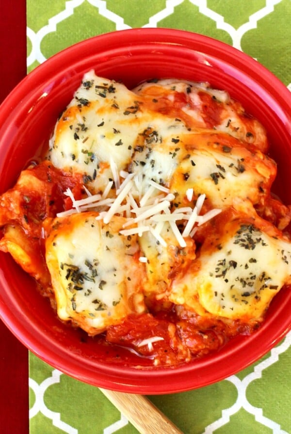 Red bowl of ravioli with sauce.