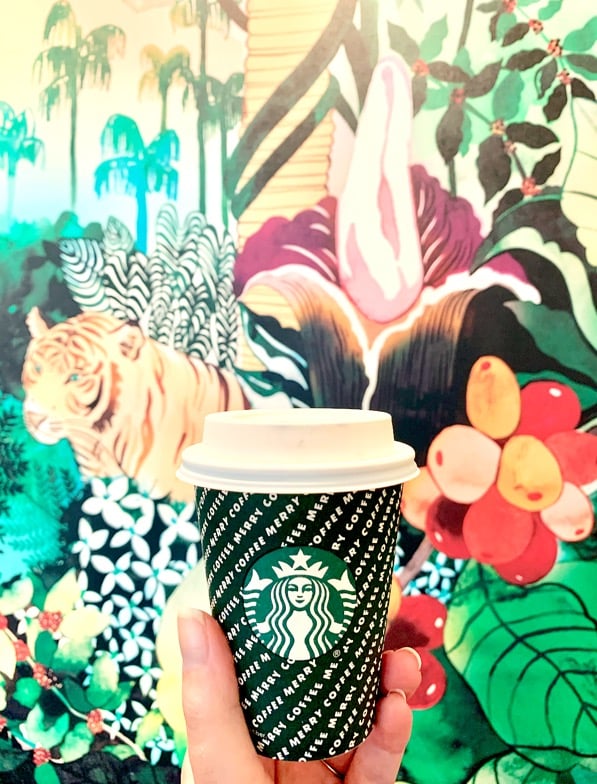 Short Starbucks cup in front of mural.