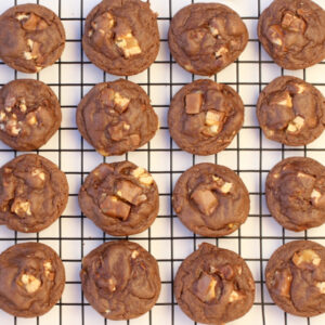 Snickers cookies cooling on a wire rack.