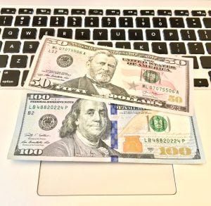 A $50 bill and a $100 bill on a keyboard.