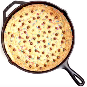 Baked chocolate chip skillet cookie with sprinkles in cast iron skillet.