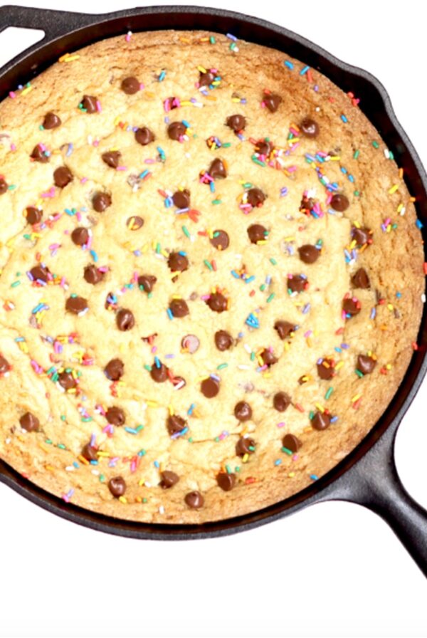 Baked chocolate chip skillet cookie with sprinkles in cast iron skillet.