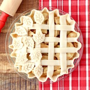 Apple Pie with lattice and leaf crust and rolling pin to the side.