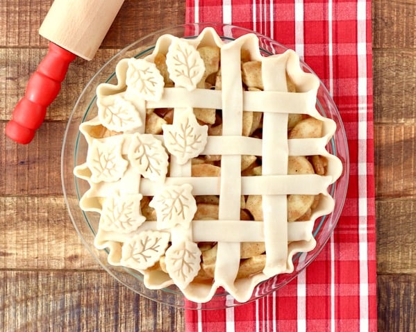 Apple Pie with lattice and leaf crust and rolling pin to the side.