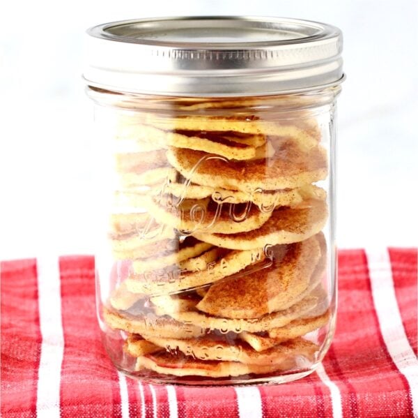 Apple chips stacked in mason jar with a lid.